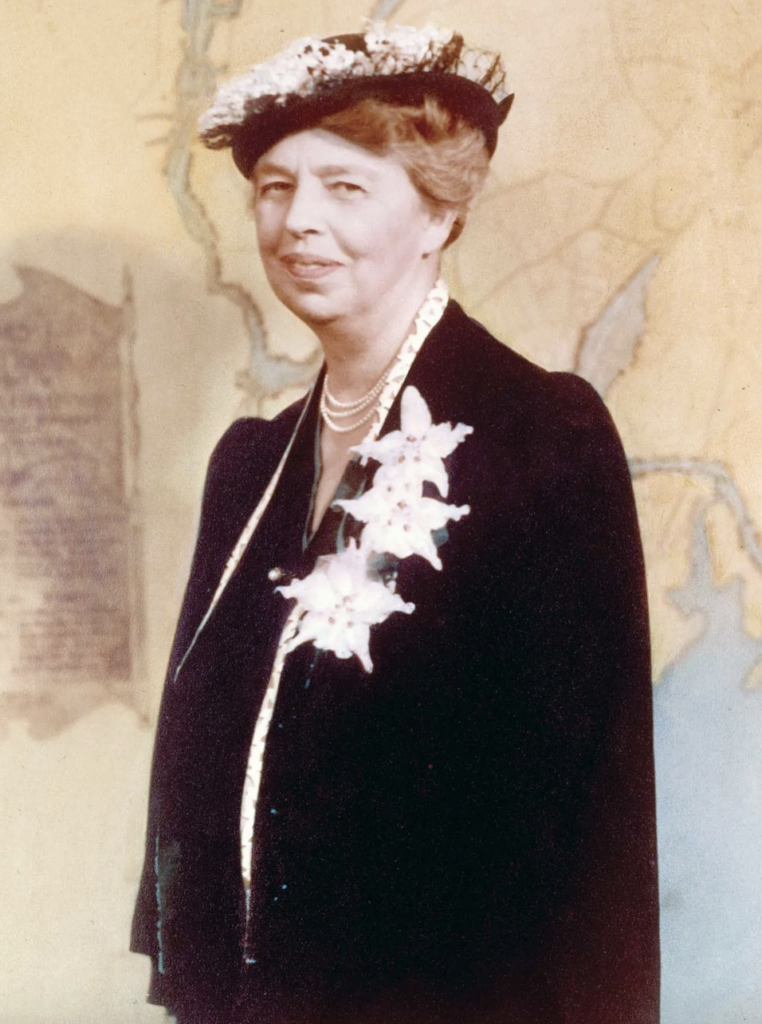 Photograph of Eleanor Roosevelt in a black dress with white accessories and white hat on yellow background.